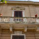 Il piano superiore invece, riproponendo lo schema tripartito di quello inferiore, presenta delle lesene che scandiscono i tre spazi occupati dai finestroni. Al centro quattro mensoloni sorreggono un ampio balcone in pietra, abbellito da un elegante balaustra e una coppia di vasi floreali. Chiude la facciata un cornicione marcapiano che corre lungo tutto il perimetro dello stabile
